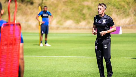 Kieran in black sportswear standing on grass.