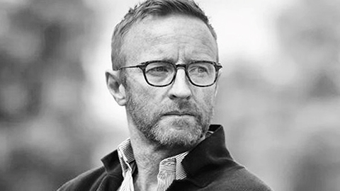 Ben Ryan looking into the distance. He wears glasses. The photo is black and white.