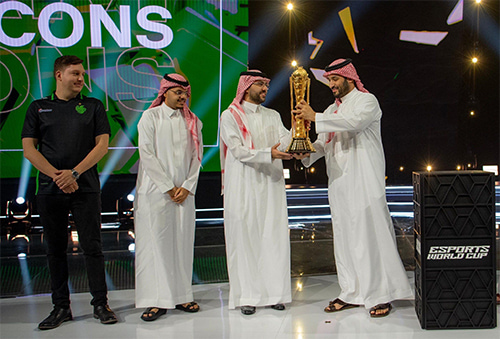 Four people on a stage. Two of them hold a trophy.
