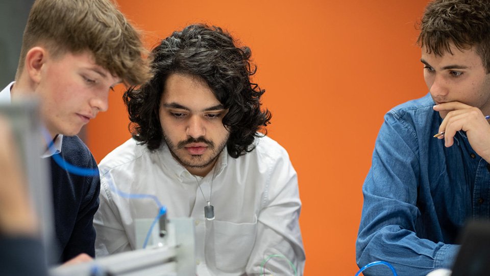 Photo of three students looking at something together