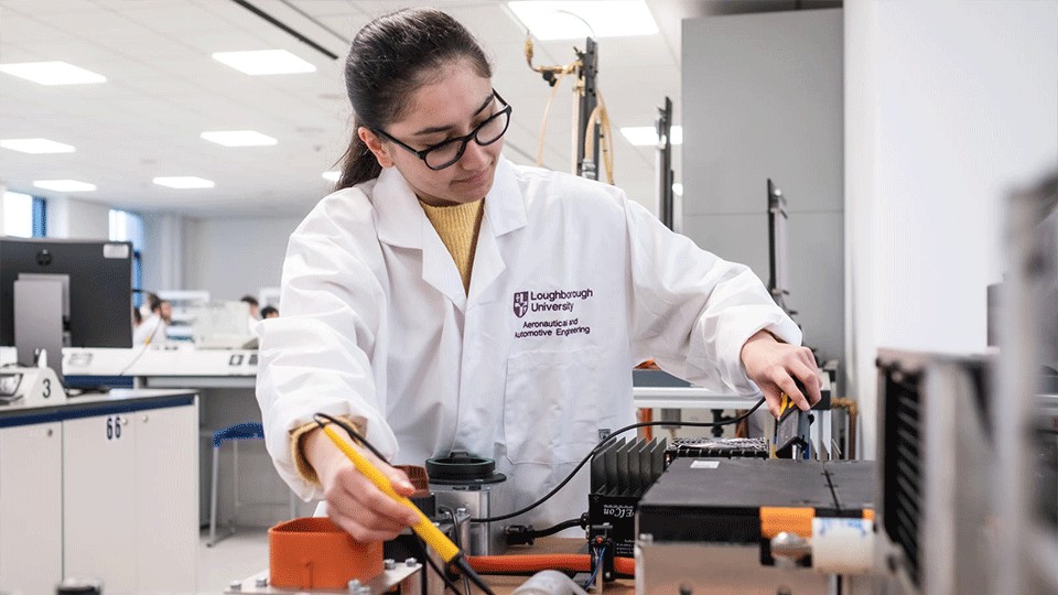 female student holding working in a lab wearing glasses and a lab coat