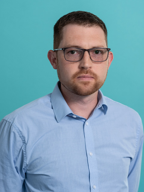 Headshot of Chris Harvey wearing blue shirt and glasses