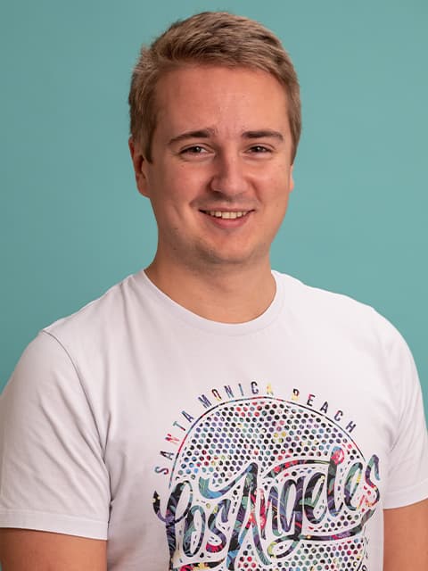 headshot of male research associate in white t-shirt with teal coloured background