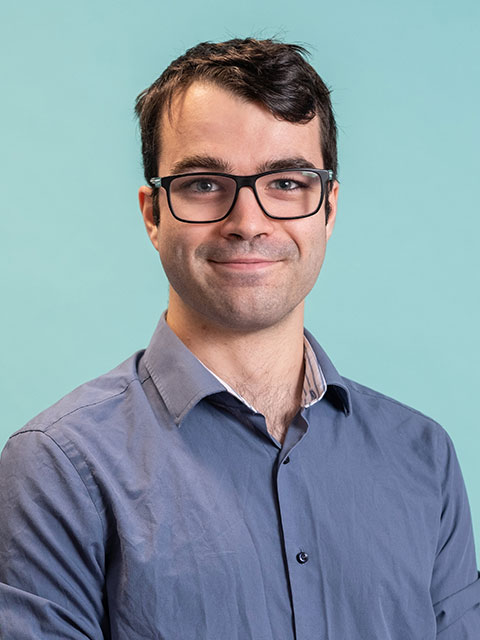 Headshot of William in blue shirt and glasses