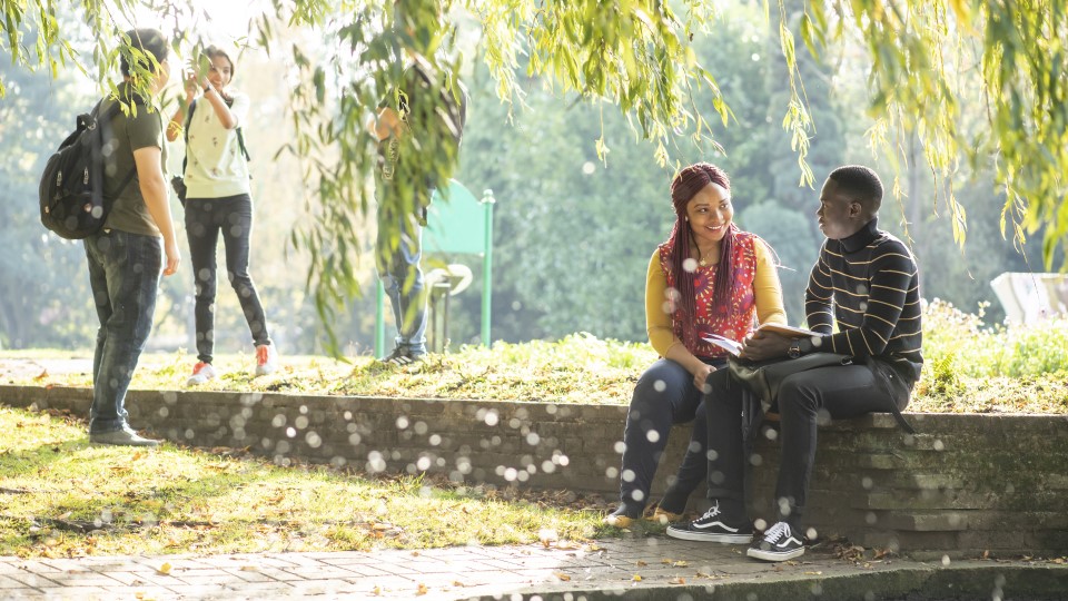 Two students sitting and two walking on campus in spring