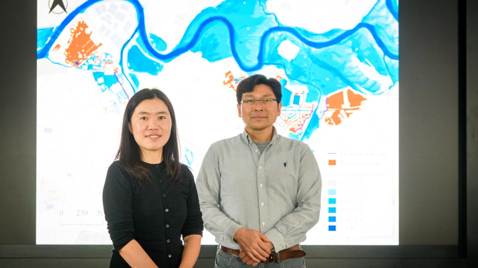 Two academics standing in front of a digital water image
