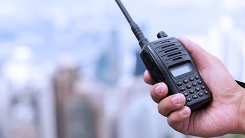 A person's hand holding a walkie talkie.