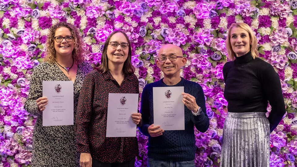 Aly Howells-Chivers, Marion Jost, Kai-Hong Tee and Jan Godsell stood in front of a flower wall.