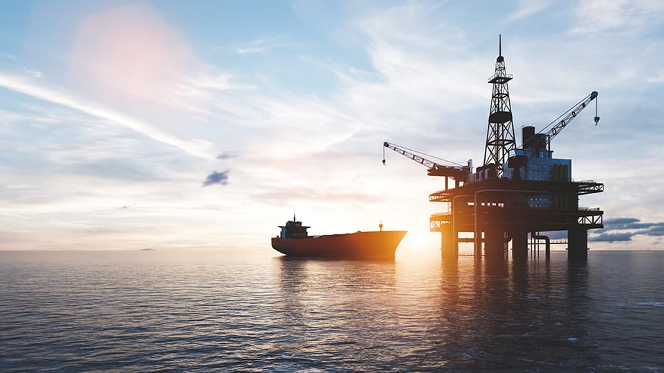 Oil platform on the ocean with a ship closeby.