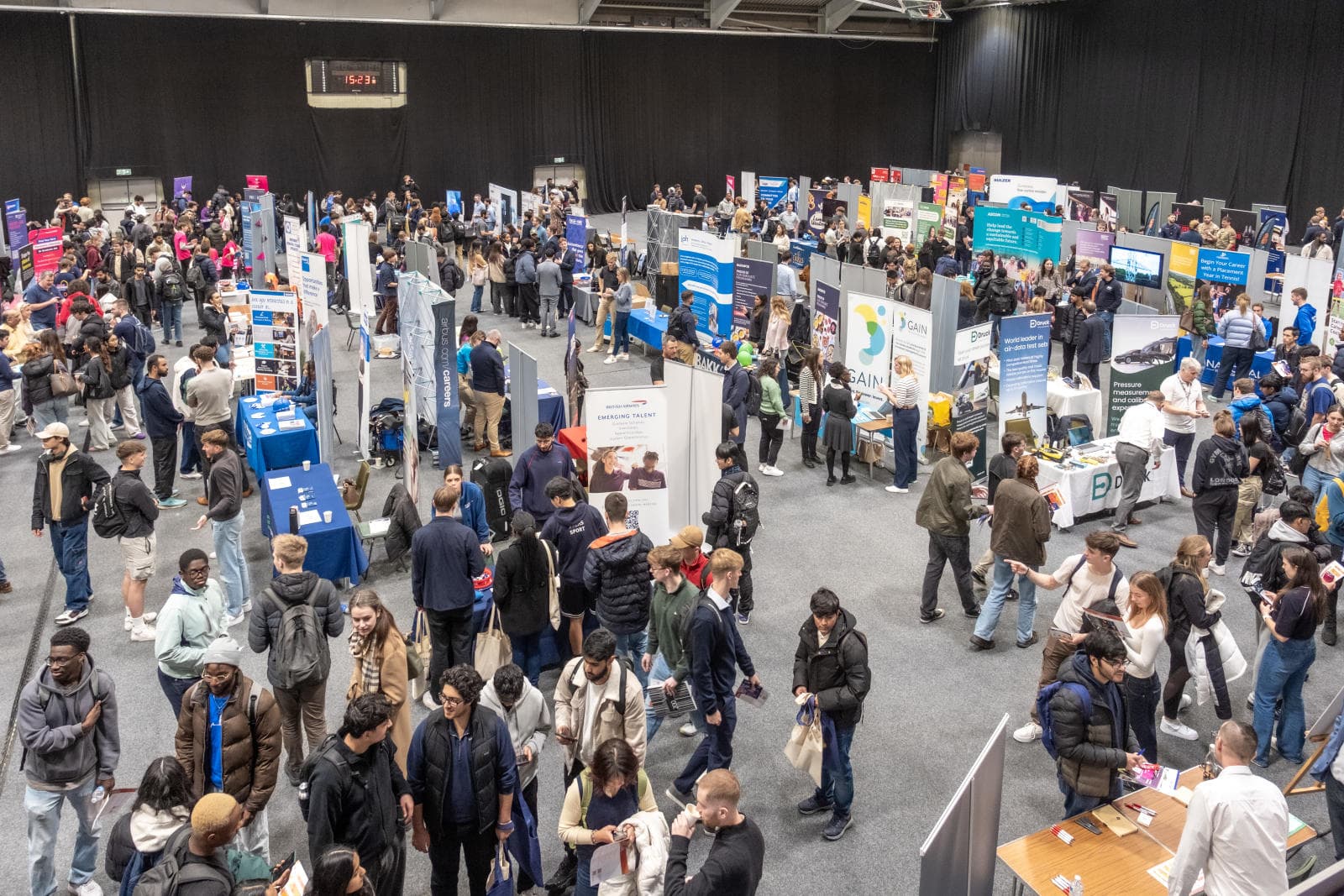 A spacious room filled with numerous career stands, bustling with a large crowd of students attending.