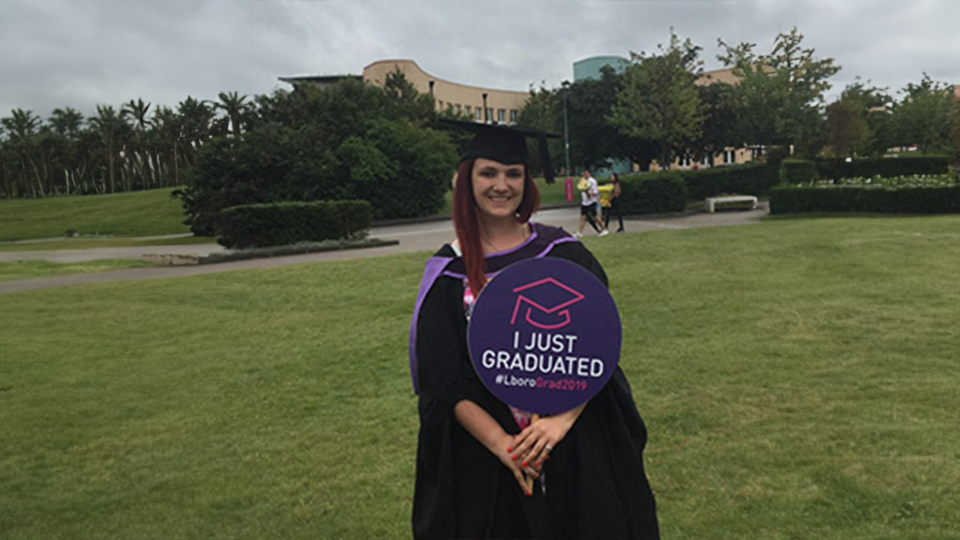 Charlotte in her graduation gown on the university campus