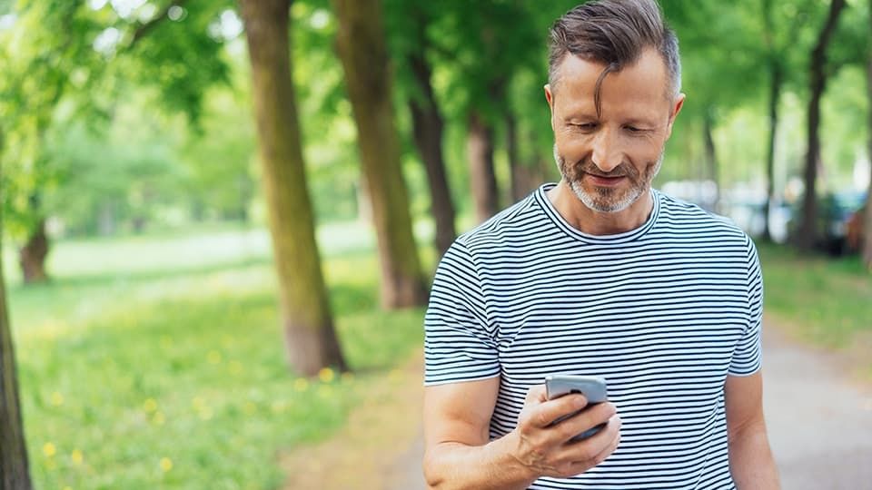 Man looking at phone near trees