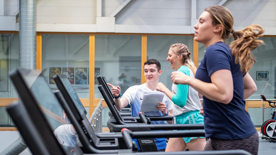 Student coaching athlete on running machine