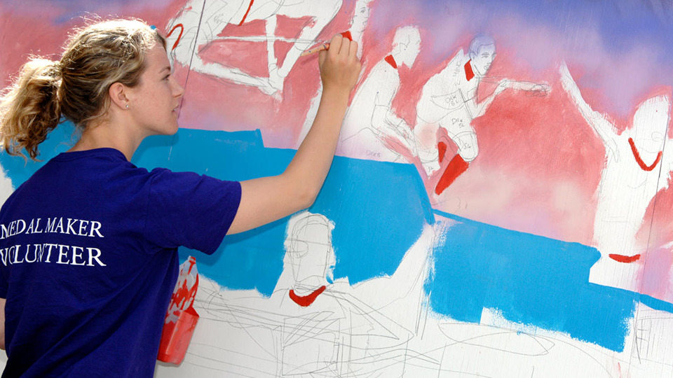 Student volunteer painting a mural