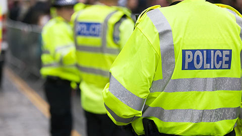 Back of a male wearing a high-vis jacket with the word police on it