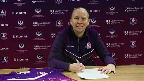 Player, Morgan Rodgers sitting a table, signing a piece of paper