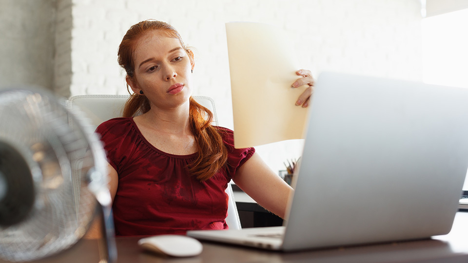 Pictured is an office worker struggling to work in the heat. 