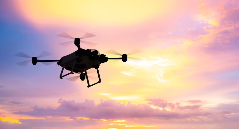 A drone flying against a pink sky 