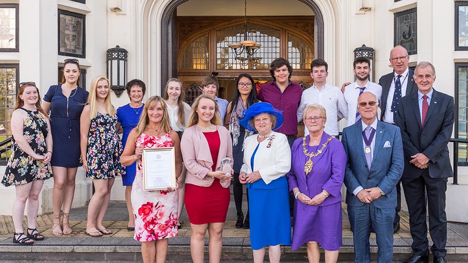 Action receiving Queen's Award at the front of the Hazlerigg building