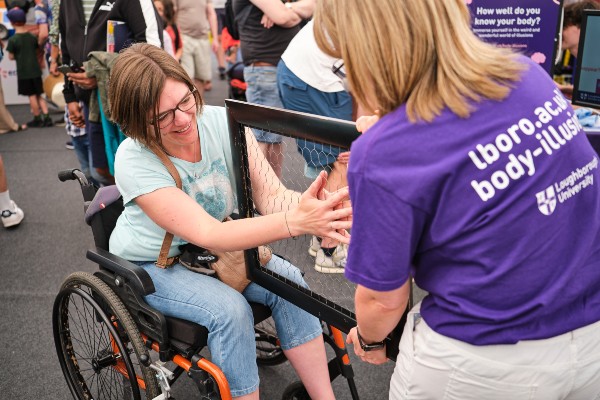 A woman engaging in an optical illusion being held by another woman