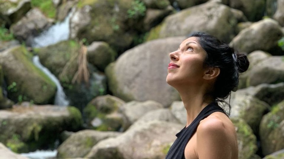 Becky Lyon looking up to the sky with moss covered rocks in the background.