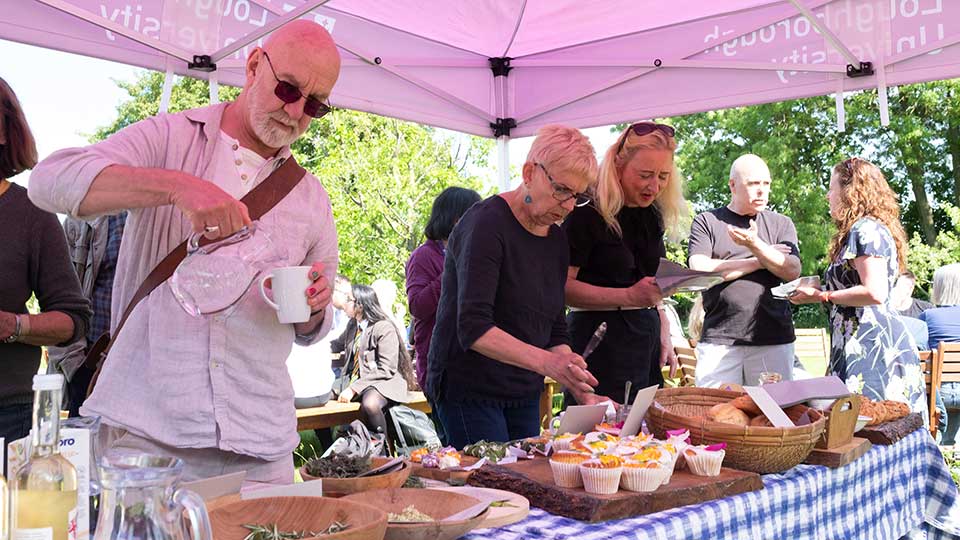 People serving themselves from a buffet in a tent outdoors