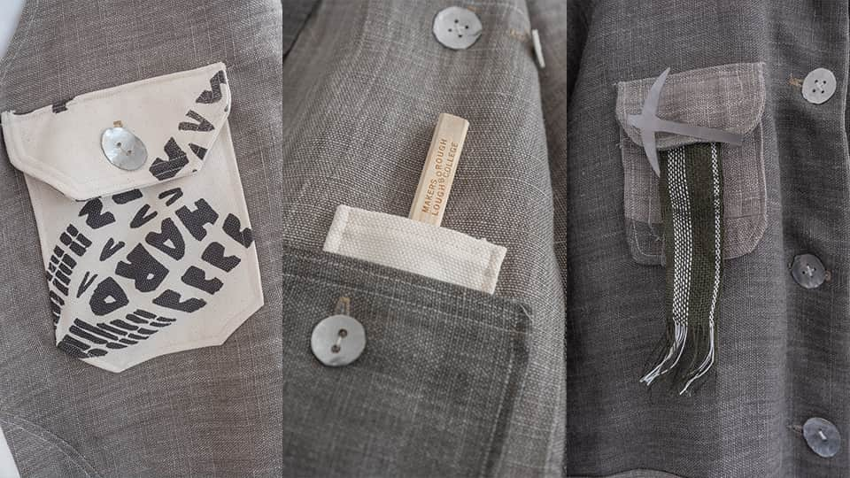 A handmade grey jacket with silver buttons and three pockets.