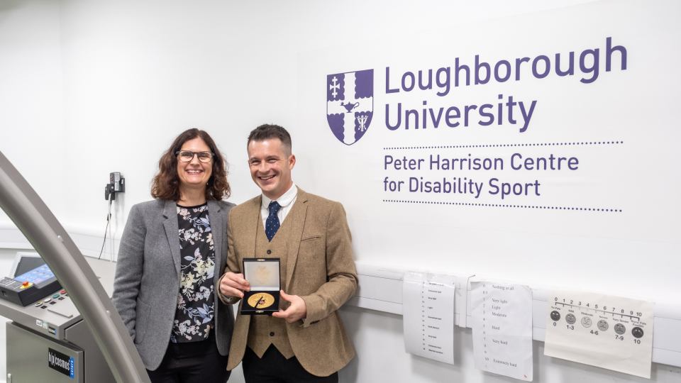 Jonathan in a suit smiling with his University medal stood next to Professor Vicky Tolfrey