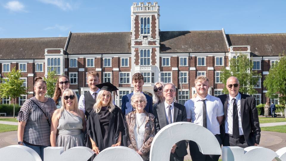 Photo of Sandra Freeman and Molly Jackson with their family outside the Hazlerigg Building on graduation day