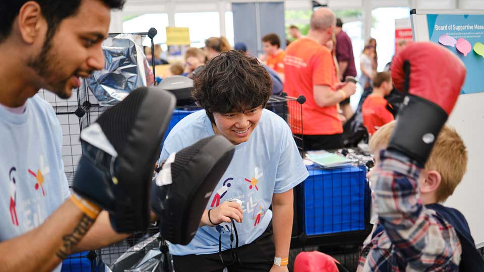 Volunteers guiding a young visitor through the boxercise activity