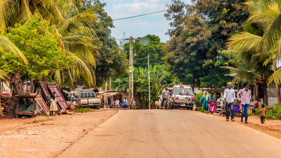 A road running through an African village, with people going about their daily activities