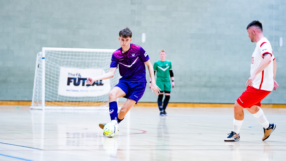 a man playing futsal with a defender closing him down