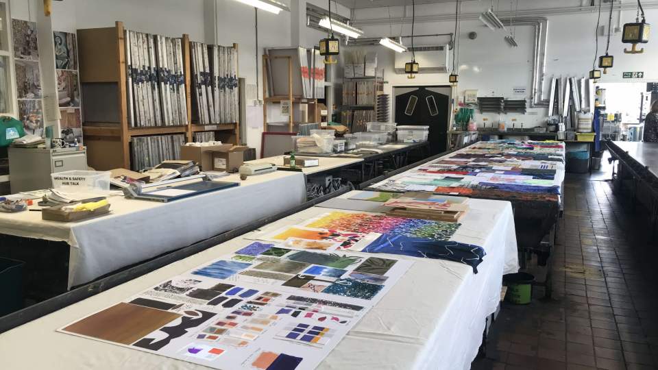 A textiles workshop with mood boards and fabric samples laid out on tables.