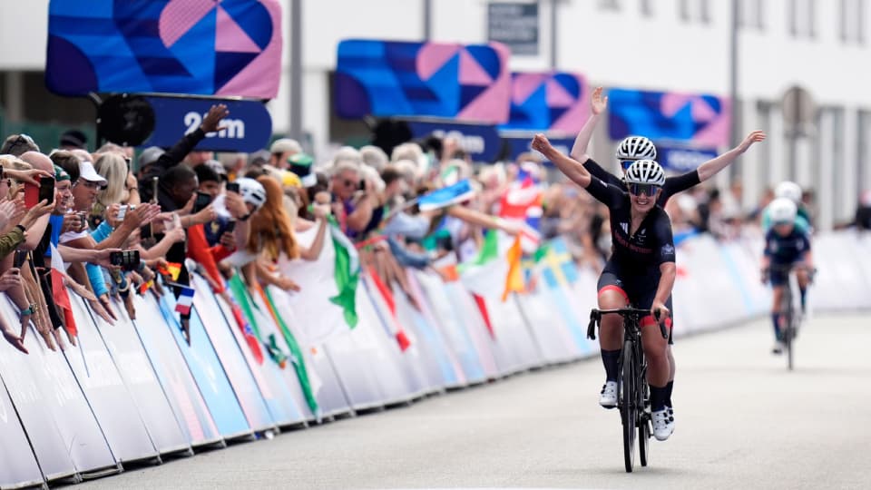 jenny holl, a cyclist, lifts her arms aloft on her bike after winning gold in paris