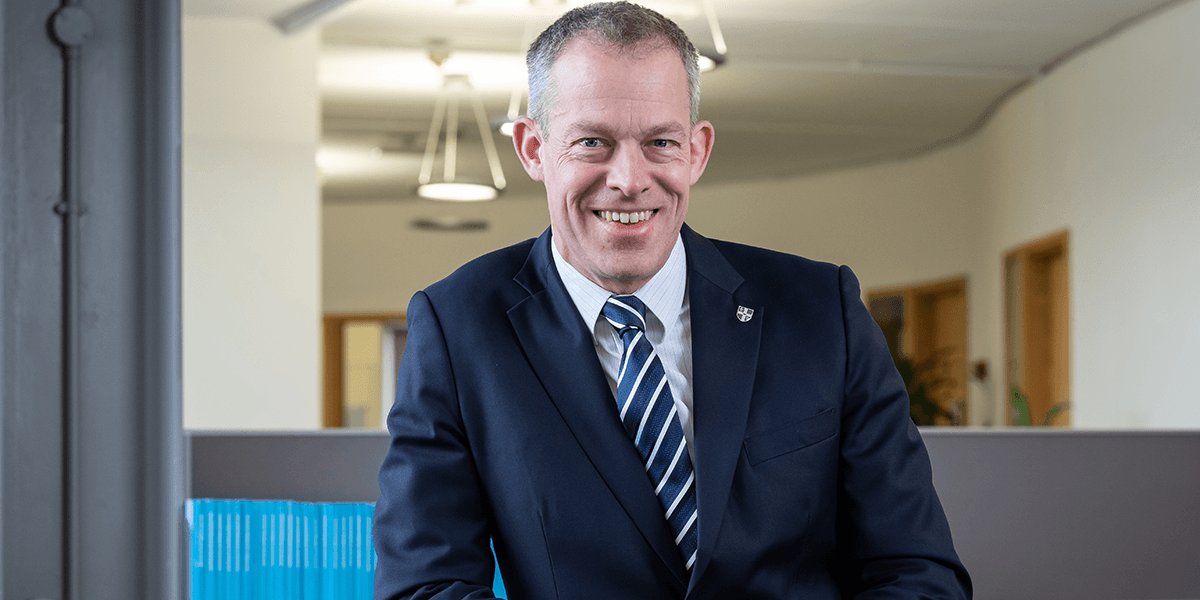 Man in suit smiling against a white background