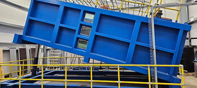 the National Engineered Slope Simulator (NESS), which is a 15-tonne steel box (6m long, 3m wide, 2m tall) that can be filled with 45 tonnes of compacted soil, then rotated to create a slope, and then subjected to simulated weather patterns