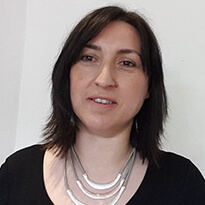 Female graduate smiling in front of a white wall