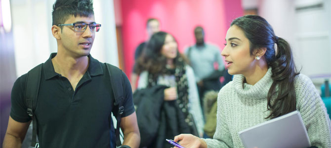 Two researchers in conversation walking along a corridor