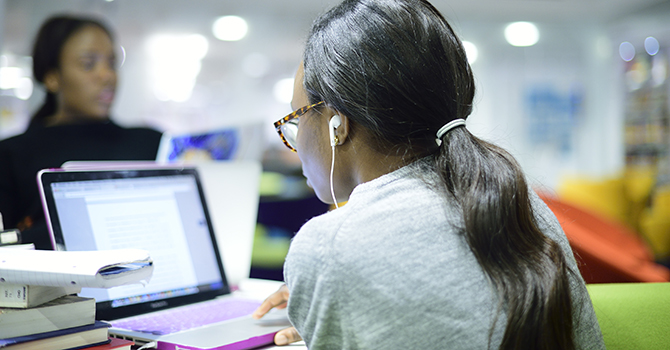 Woman using a purple laptop in the library.