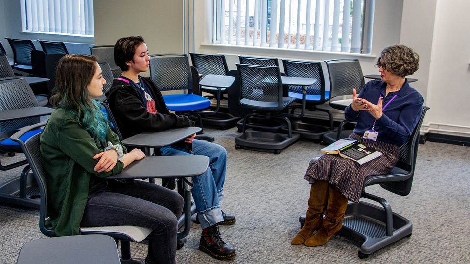 Two students sat listening to Carolyn Scott-Jeffs who is sitting in the chair opposite.