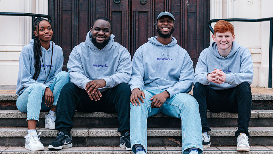 Four Nestwork founders sat on the steps of Hazlerigg