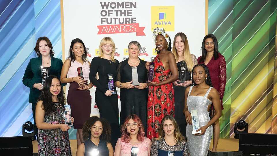 A group of people stood together holding trophies at the Women of the Future Awards.