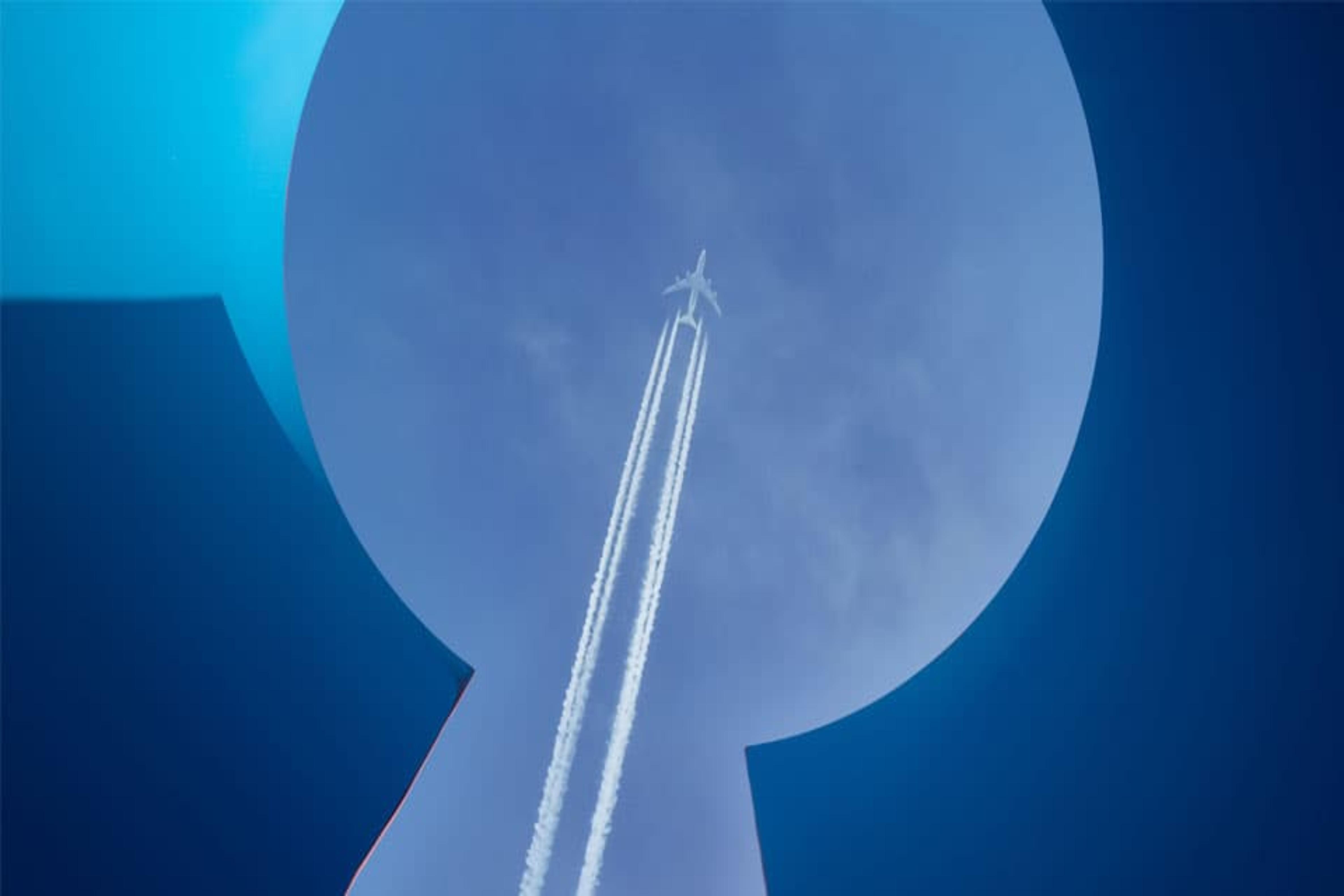 An abstract photo of a plane flying in the sky seen through a keyhole shape.